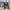 Person walks through an old stone archway in a historic, cobblestone plaza.