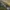 Tall rock spires rise from a forested hillside in a mountainous landscape.