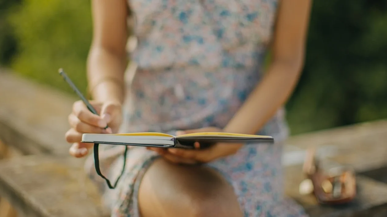 Woman writing in a notebook in the palace garden of Sanssouci Palace, Germany