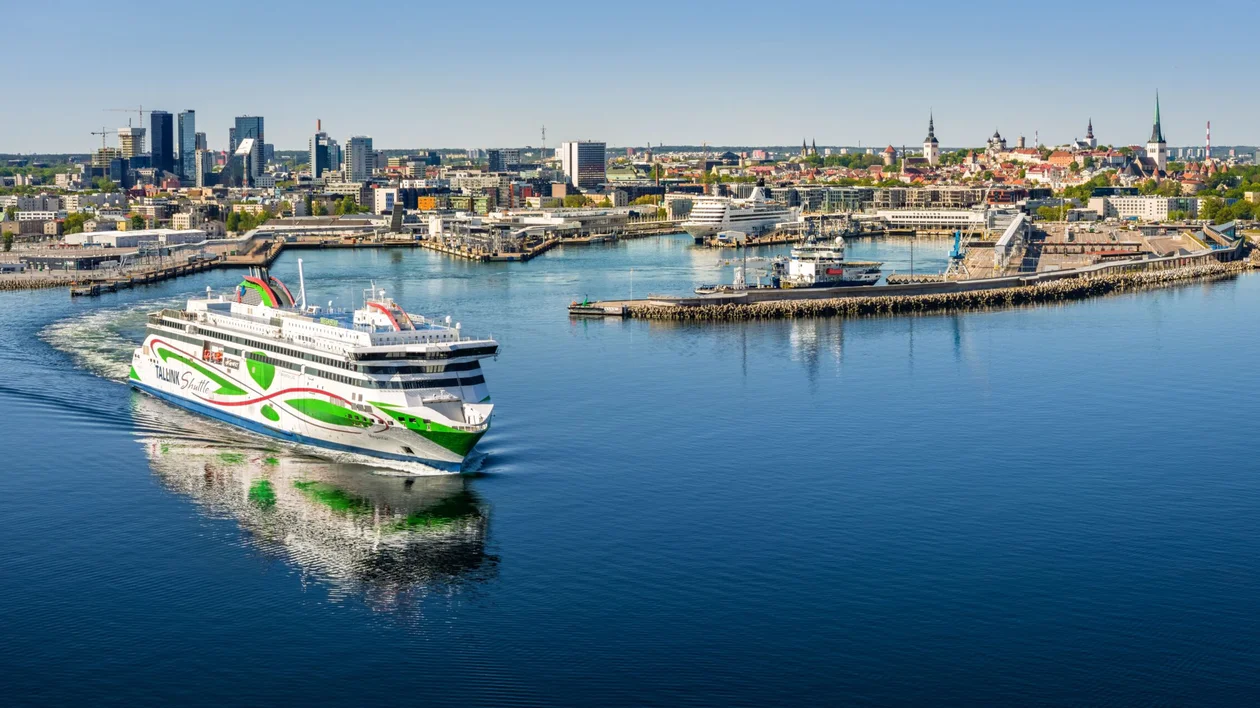 A large cruise ship in an harbor, surrounded by a cityscape composed by medieval buildings and skyscraper in the distance.
