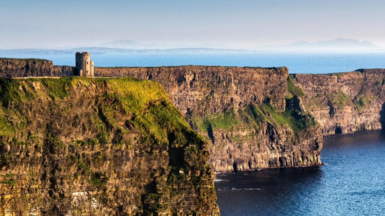 Ancient stone tower atop steep cliffs overlooking the sea.