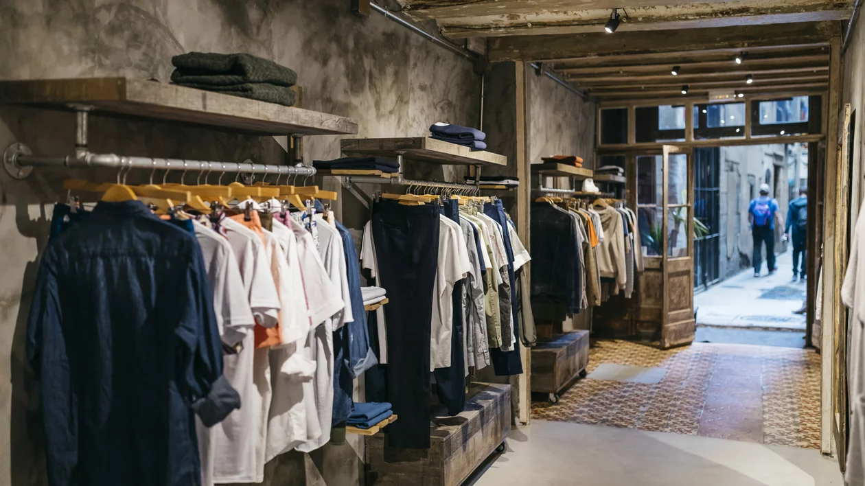 A boutique showcasing arranged racks of clothing in a rustic interior.