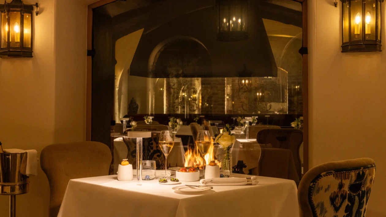 Elegant restaurant interior with set tables, candlelight, and wall lanterns.