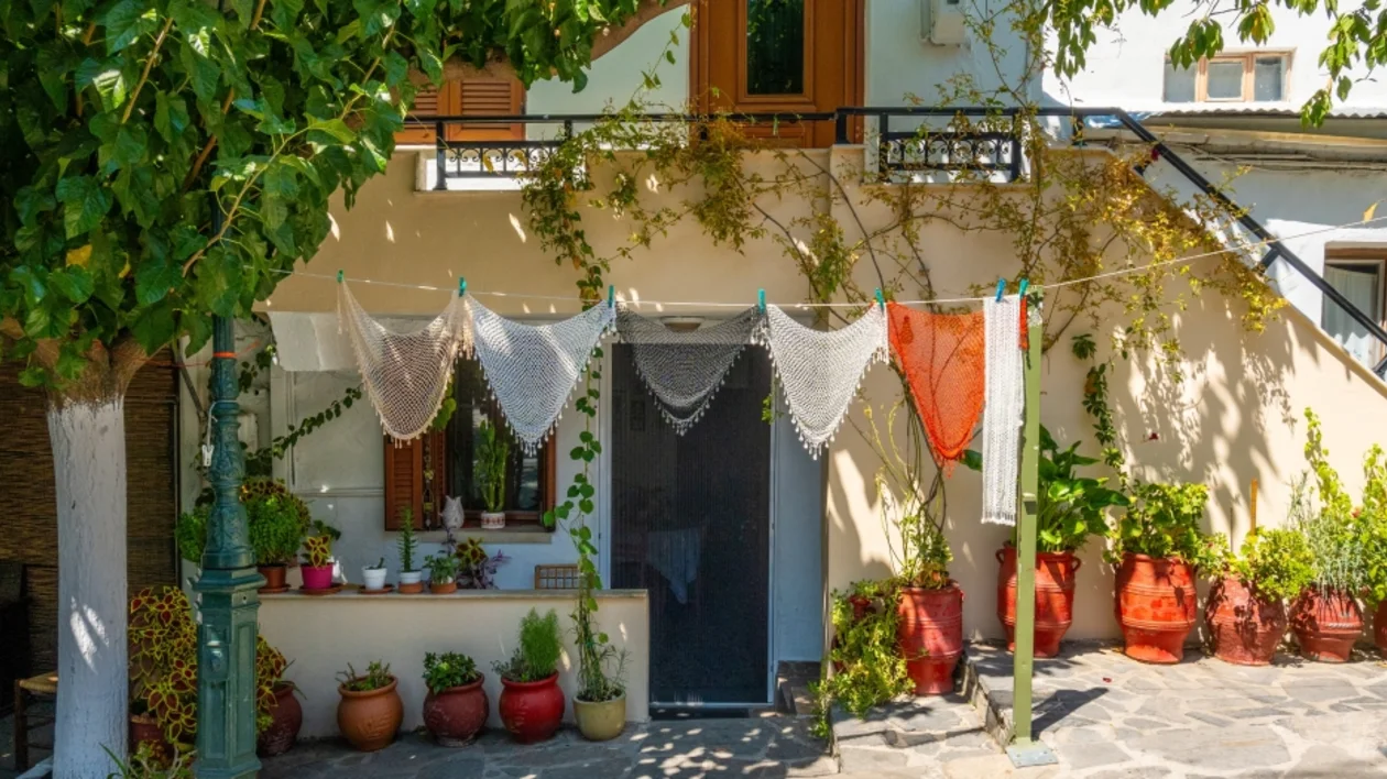 Quaint house front with hanging lace, plants in pots, and a green lamp post.