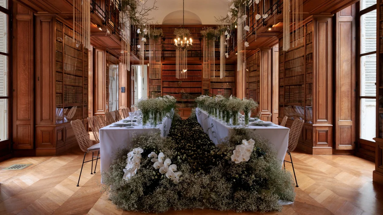 Elegant dining room with lavish floral table decor and wooden bookcases.