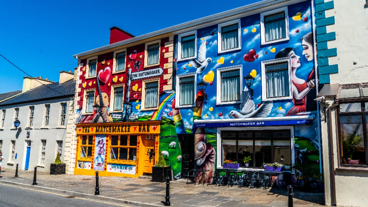 Colorful mural on a bar with heart and bird motifs, under a clear blue sky in Lisdoonvarna, Ireland.