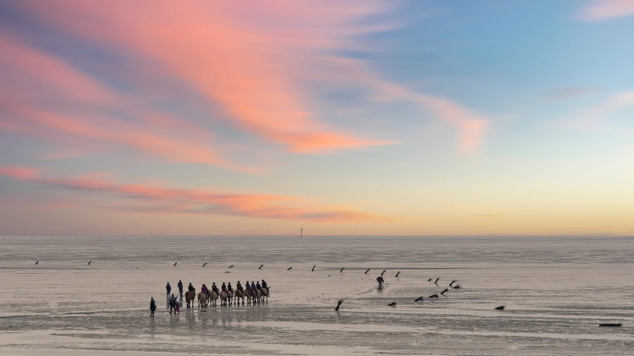 A tranquil beach scene with wicker beach chairs scattered on the sand, under a soft pastel sky at sunset.