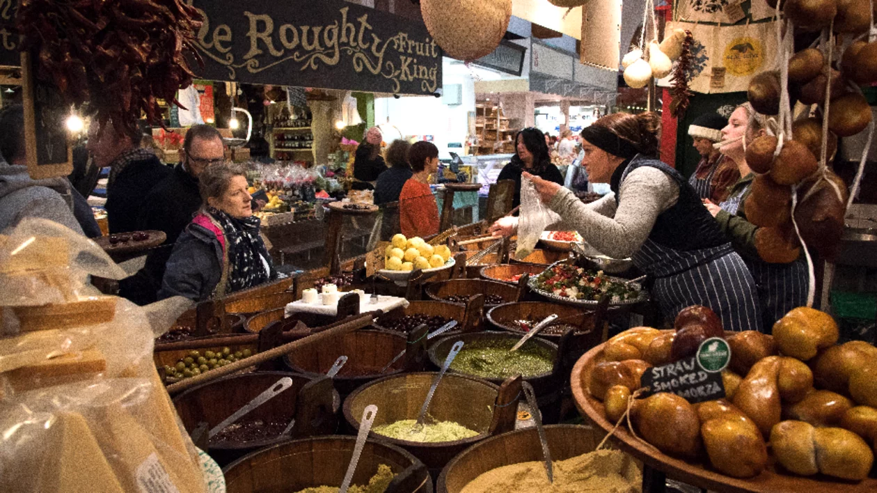 A bustling market scene filled with colorful produce, spices, and jars, as shoppers and vendors interact amidst vibrant displays.