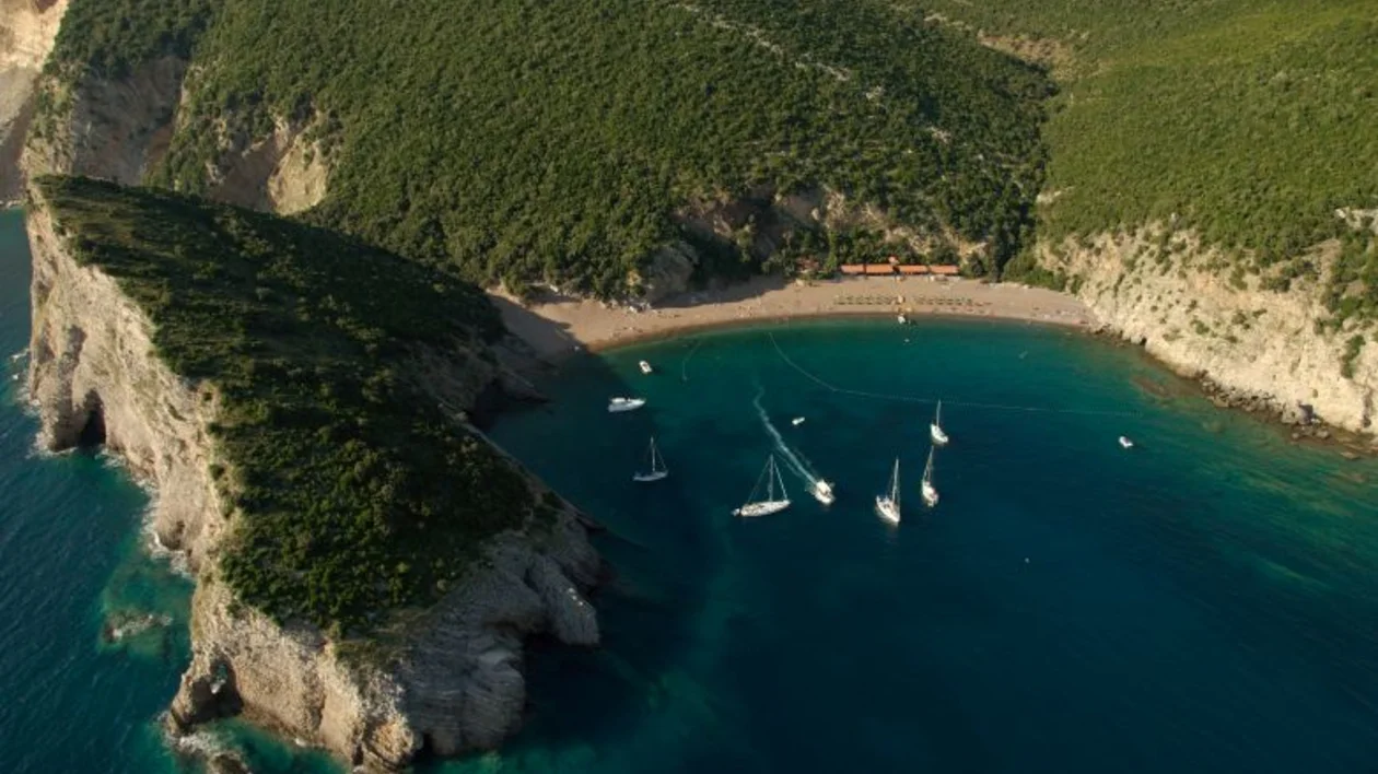 Aerial view of Queen’s Beach, a secluded cove with yachts anchored in clear blue water near Budva, Montenegro.