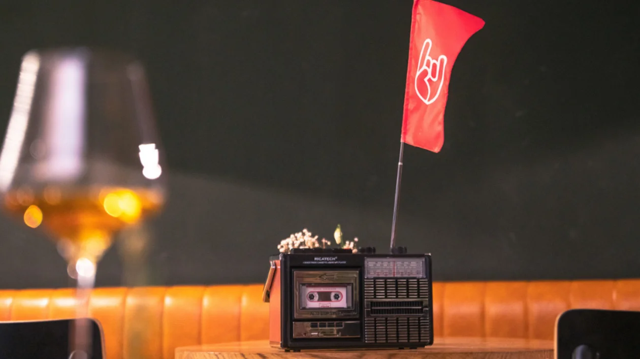 Glass of orange wine beside a vintage cassette player with a red flag in Slovenia.