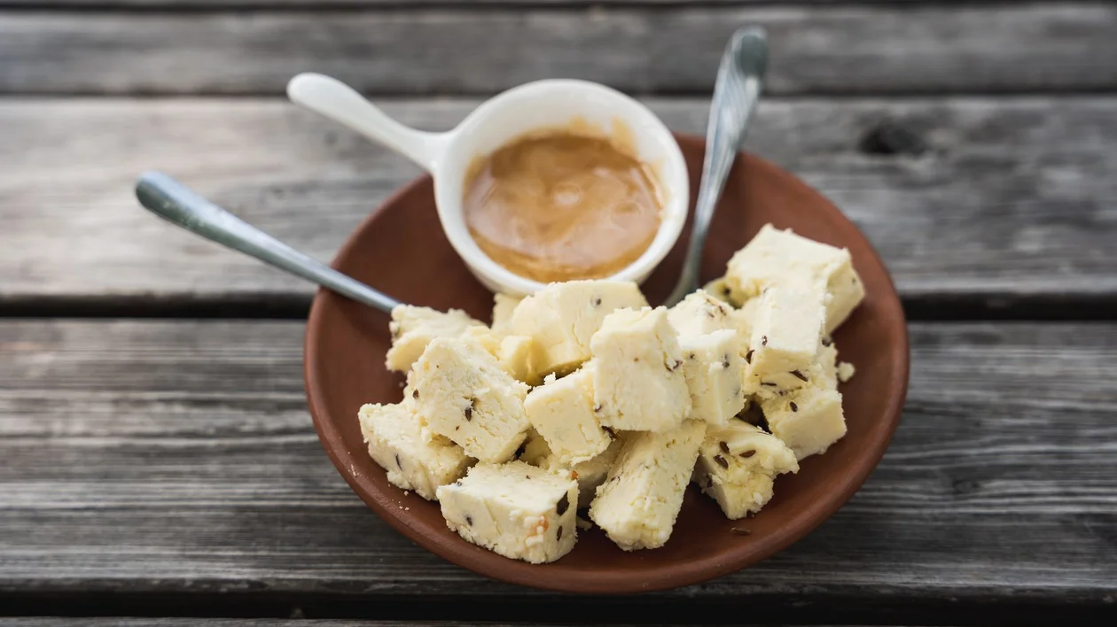 Plate of Estonian farmhouse cheese cubes with caraway seeds, served with a small dish of jam or sauce at Taarka Taro KöögiKono restaurant.