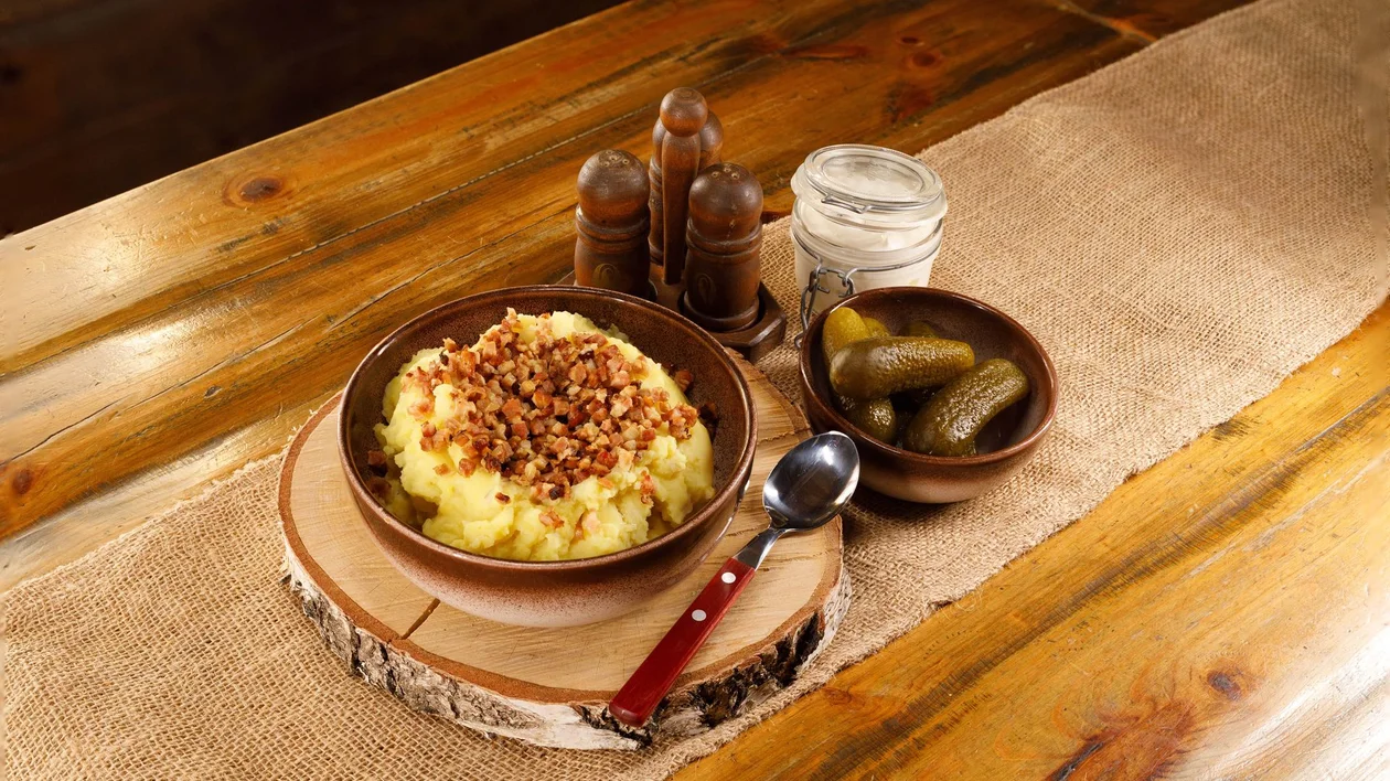 Traditional Estonian dish of mashed potatoes with fried bacon bits, served with pickles and sour cream at Kolu Tavern in the Estonian Open-Air Museum.