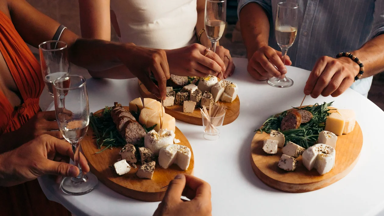 Friends enjoying local cheese and charcuterie tasting with glasses of wine at a social gathering in Europe.