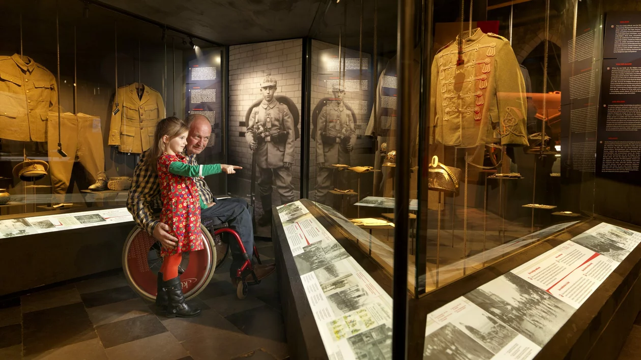 “Inside the museum, a girl pointing at the soldier section while accompanied by an adult in a wheelchair.