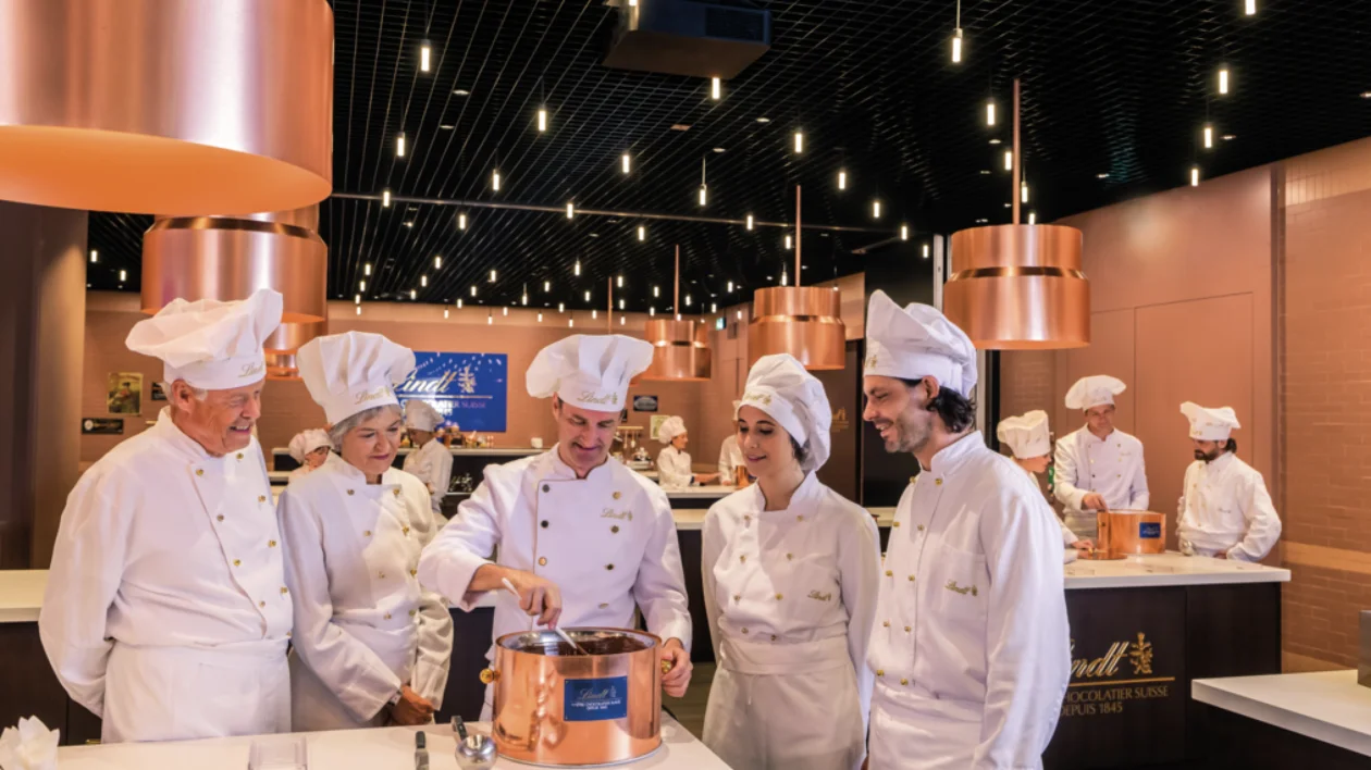 Chocolate factory workers dressed in uniforms preparing chocolate at the Lindt company.