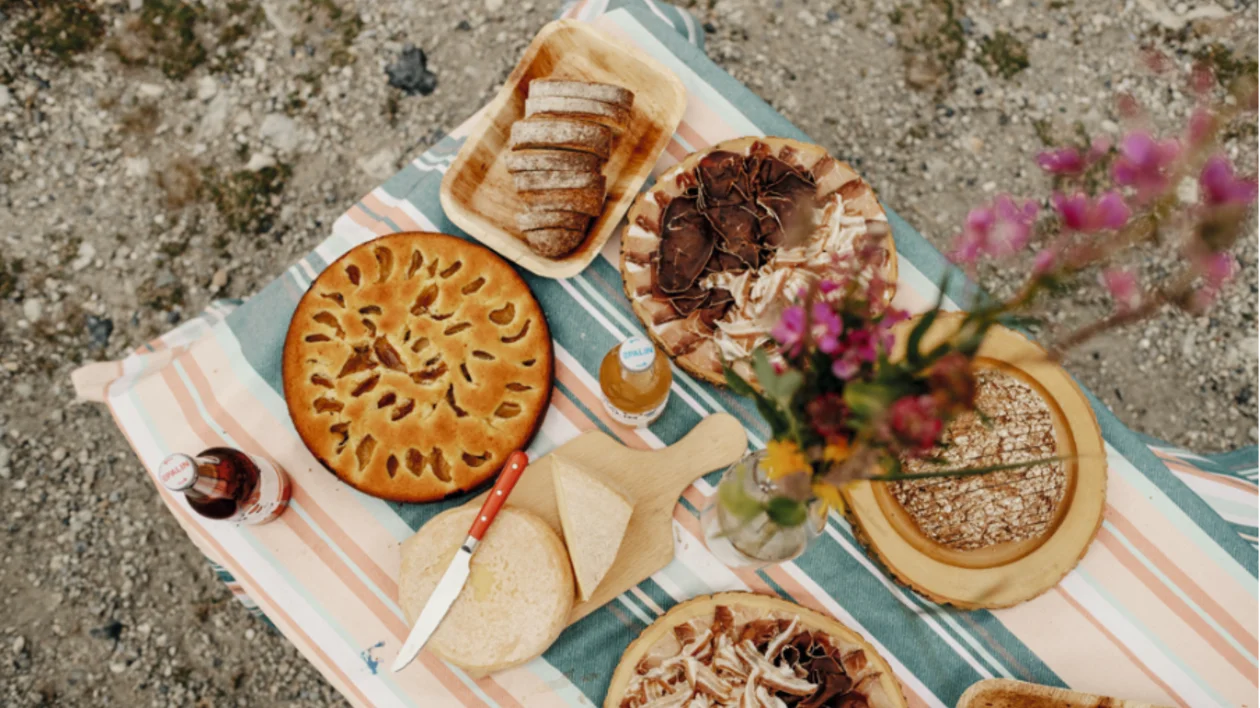 Delicious sweet fruit pie and savory ham and cheese pie resting on a cozy picnic blanket with a flower, perfect for an outdoor meal.