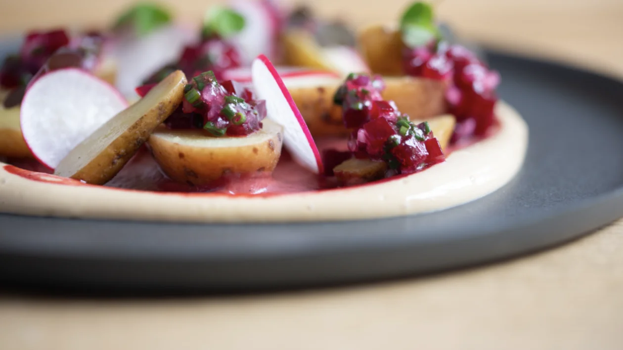A beautifully plated gourmet dish with crisp radishes resting on silky potato purée, served on classic Swiss tableware.