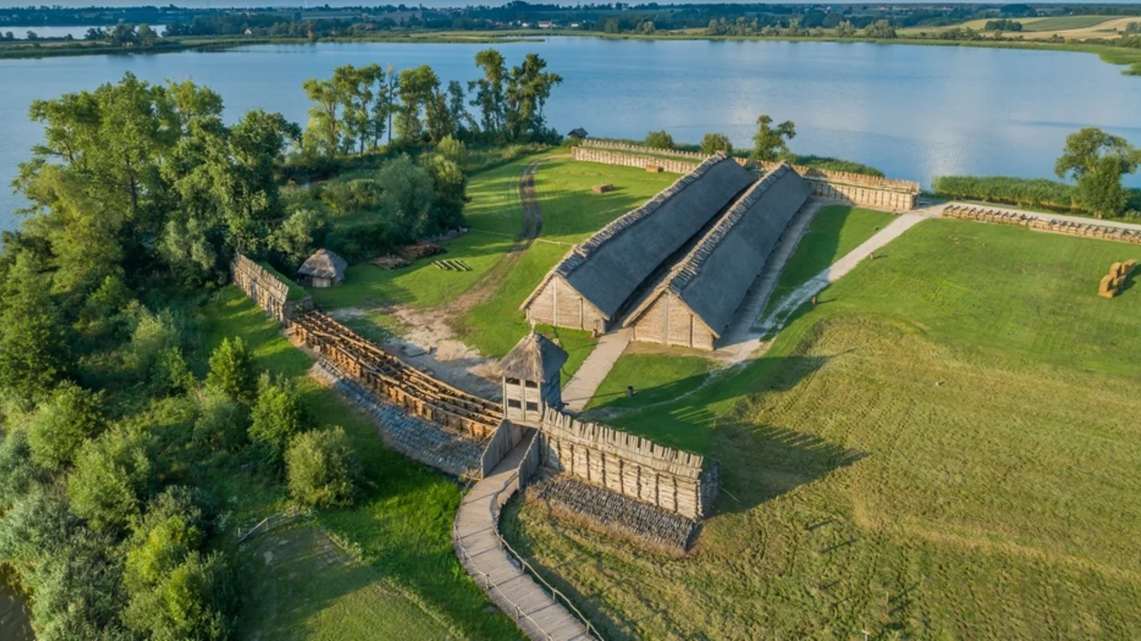 Aerial view of the reconstructed prehistoric settlement of Biskupin surrounded by wooden fortifications and a lake in Poland.