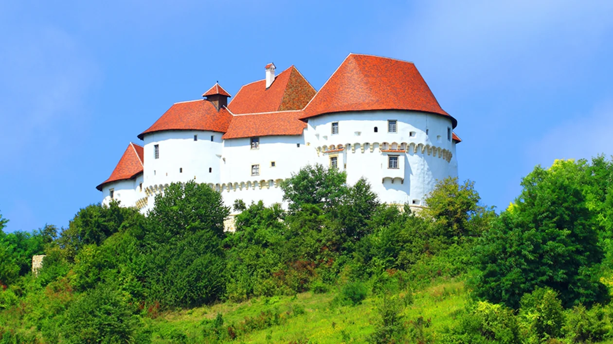 Veliki Tabor Castle perched on a green hill, with white walls and red-tiled roofs overlooking the Zagorje landscape.