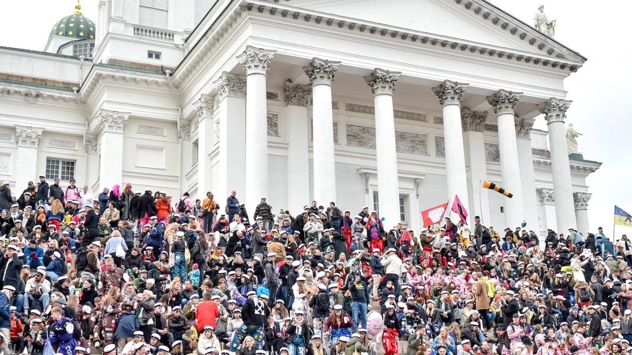 Large crowd gathered on steps in front of a white domed cathedral.