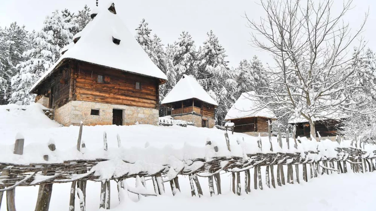 Snow-covered traditional wooden houses in Sirogojno village, Serbia.