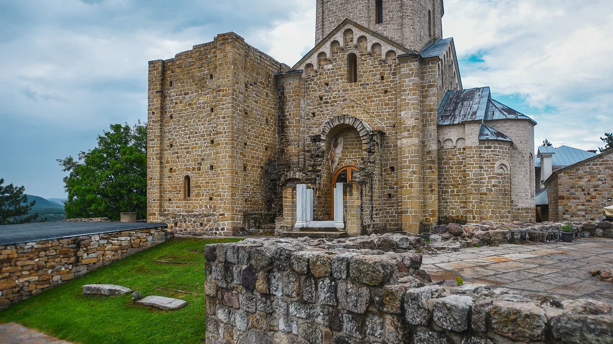 Stone medieval church with arched entrance and cloudy sky in the background.
