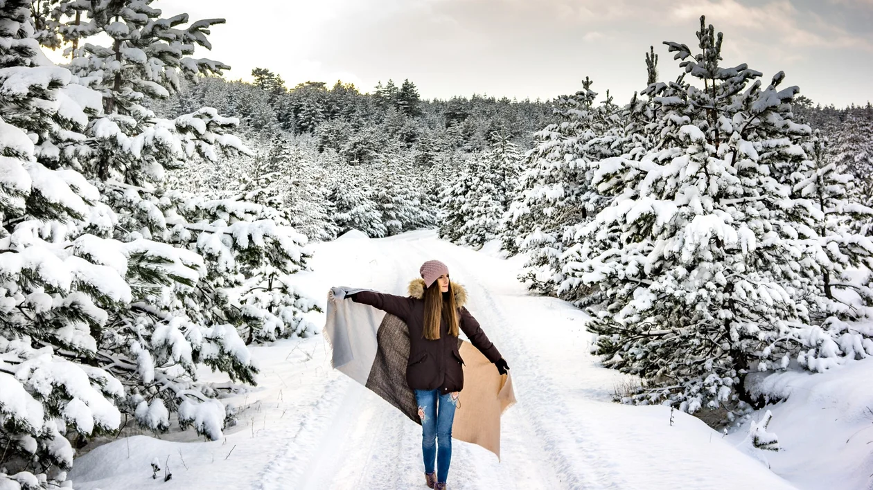 Woman walking along a snowy forest road in Zlatibor, Serbia