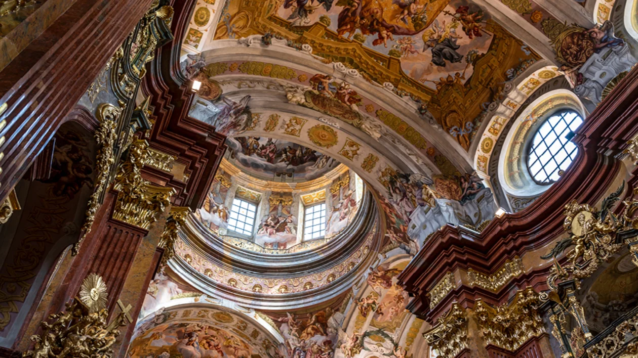 Baroque interior of Melk Abbey church in Austria with ornate frescoed ceiling and gilded columns.