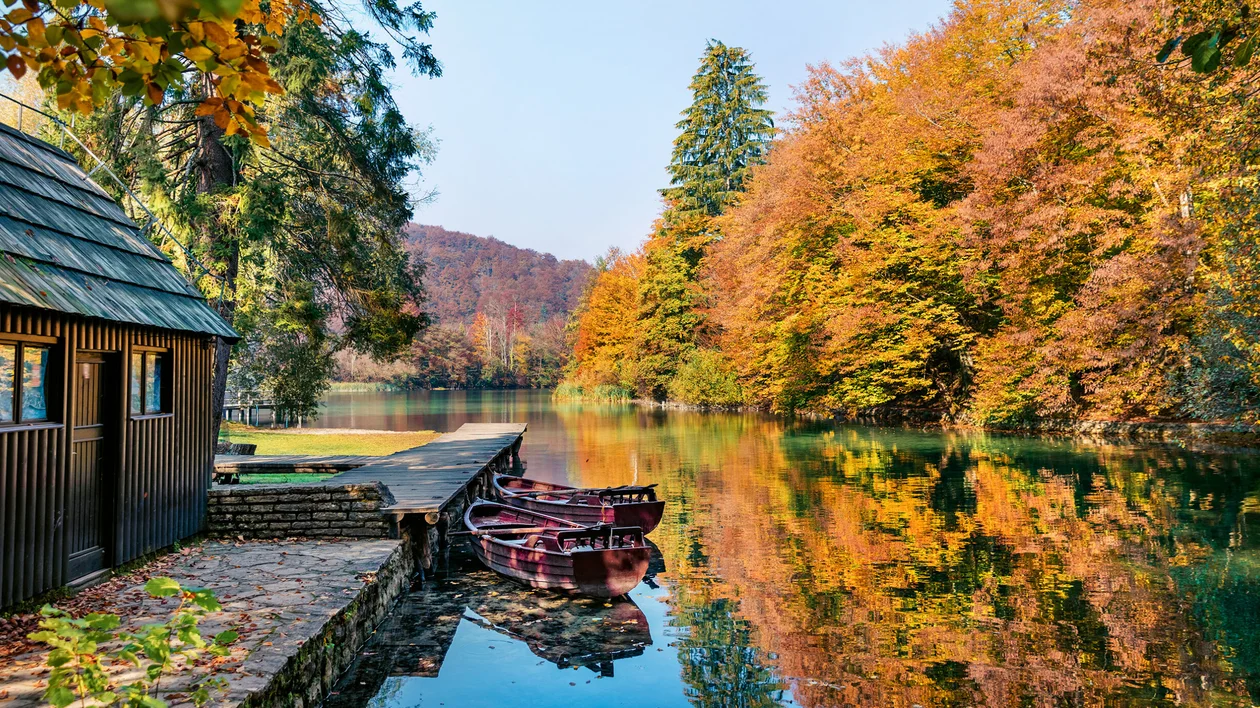 Wooden boats tied beside a calm autumn lake