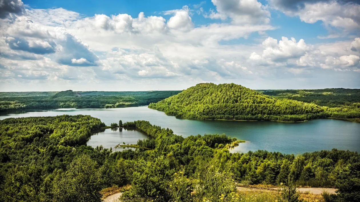 Green hills surrounding a winding river under a bright blue sky with scattered clouds.