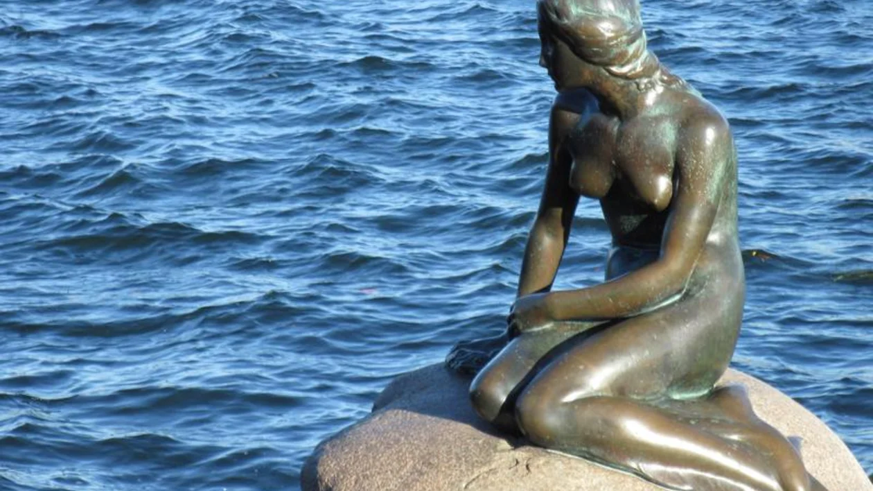 The statue inspired by The Little Mermaid overlooks the calm waters in Copenhagen, Denmark.