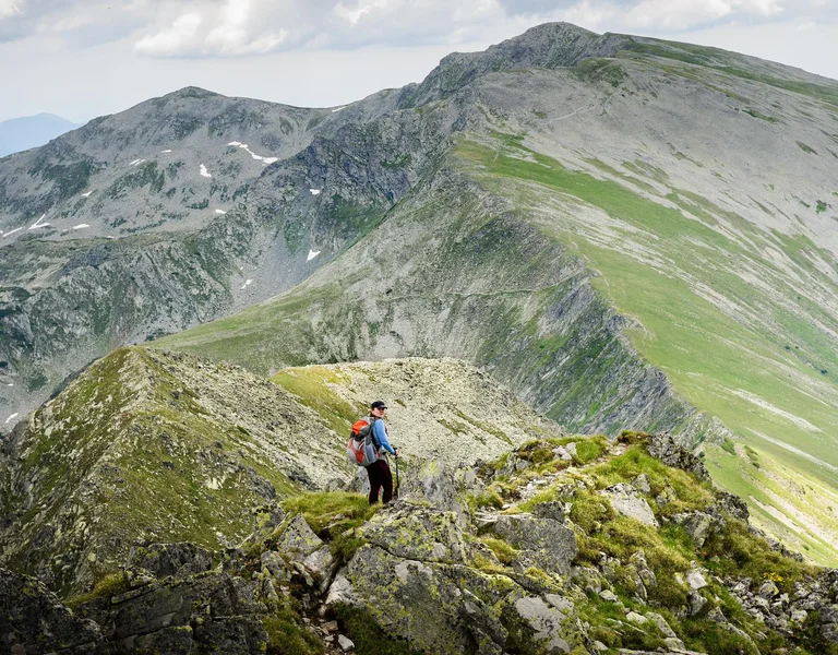 Young woman with backpack does summer hiking in the mountains in the Retezat mountains
