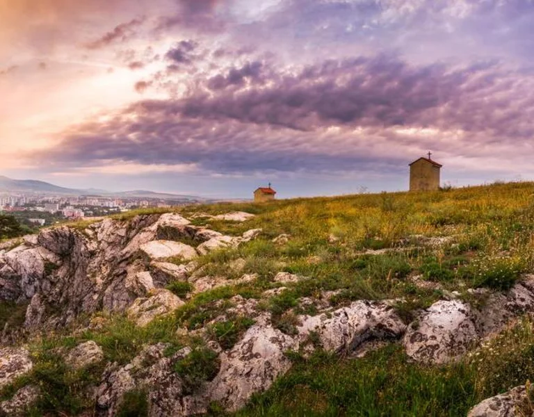 City and Village under a Hill at Sunset as Seen from Calvary, Nitra, Slovakia. Meadow with Flowers and Rocks in Foreground. © SLOVAKIA TRAVEL/Nitra Calvary