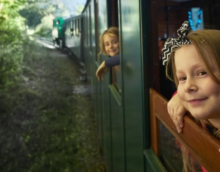 A child is looking out of the window of a train smailing
