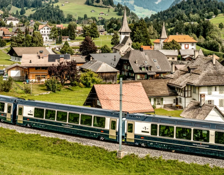 beautiful train passing though a typical swiss lanscape with small houses and trees