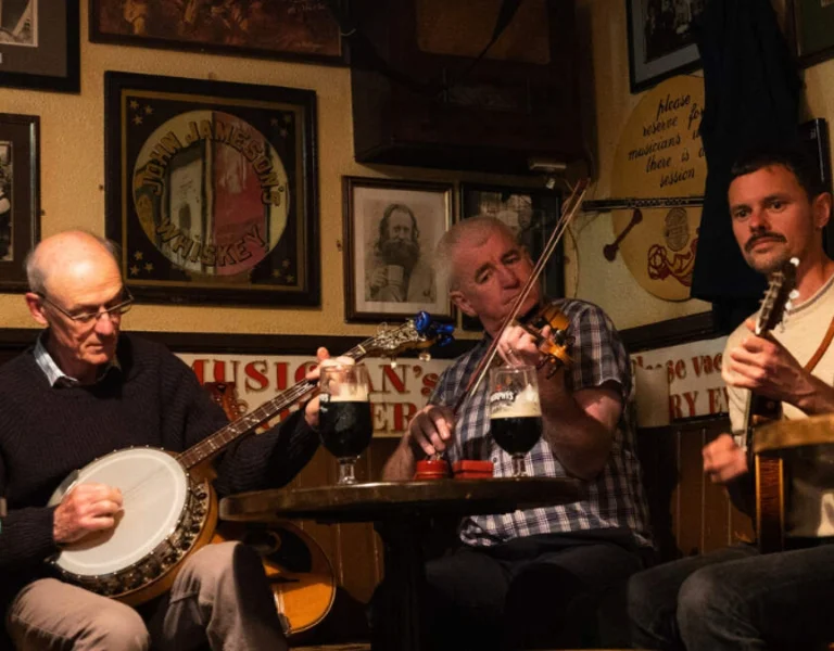 Normal people are playing their instruments sited in an Irish pub