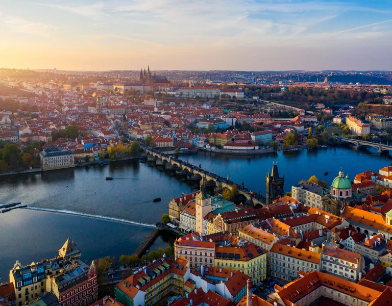 Aerial view of Prague at sunset with Charles Bridge crossing the Vltava River.