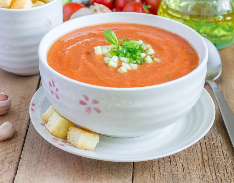 A refreshing bowl of classic gazpacho, a cold tomato-based soup originating from Andalusia, topped with chopped cucumber and fresh herbs. Perfect for hot summer days, this vibrant dish is a staple in Spanish cuisine, offering a burst of fresh, natural flavours.