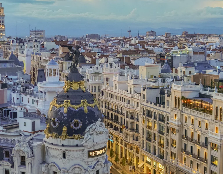 A view of Madrid's iconic Metropolis building and the city skyline at sunset.