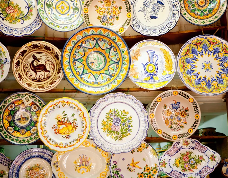 A colorful array of decorative, hand-painted ceramic plates showcasing intricate floral and animal designs.