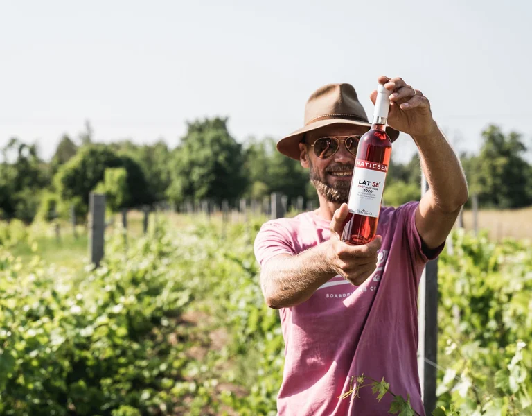 Winemaker at Matiesen Winery in Estonia holding a bottle of rosé labeled LAT 58°.