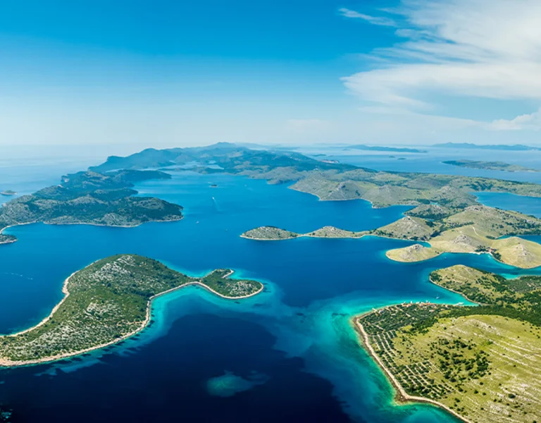 Stunning aerial panoramic view of the Kornati Islands National Park in Croatia, featuring numerous rugged green islands surrounded by deep turquoise Adriatic Sea.