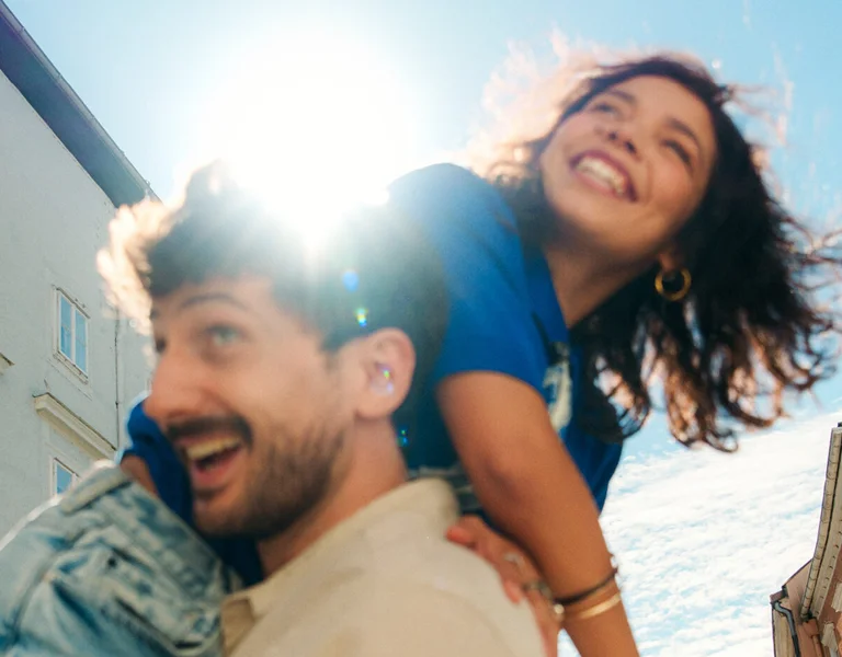 Smiling couple enjoying a sunny city break in Austria, surrounded by colorful historic buildings.