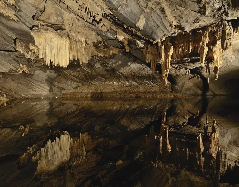 Stalactites and stalagmites reflected in an underground cave lake at the Grottes de Han in Belgium