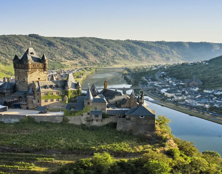 Historic European castle overlooking a river valley and vineyards, creating a fairytale landscape in Europe