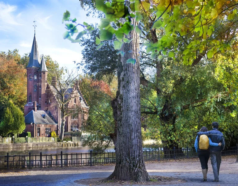 Couple walking beside Minnewater Lake in Bruges, Belgium in autumn.