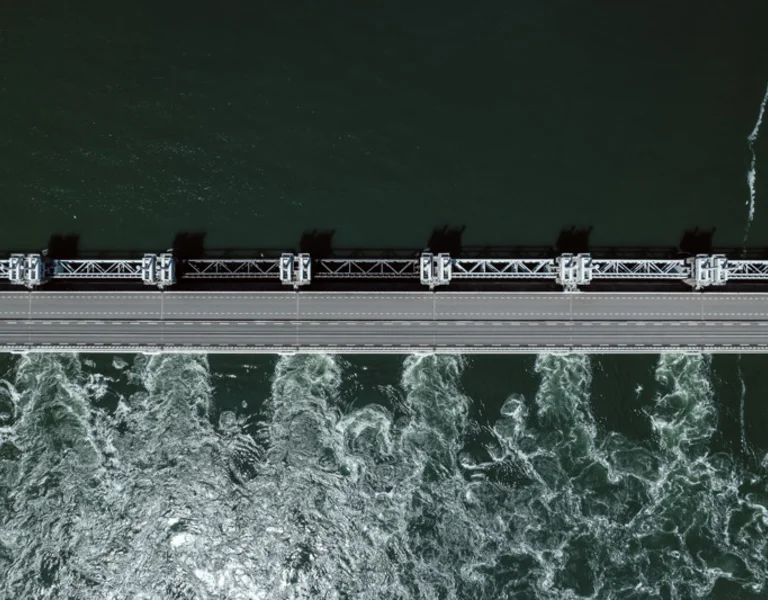 Aerial view of a dam with water flowing beneath a bridge structure.