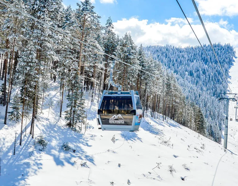 Gold gondola cable car above snow-covered forest in Zlatibor, Serbia