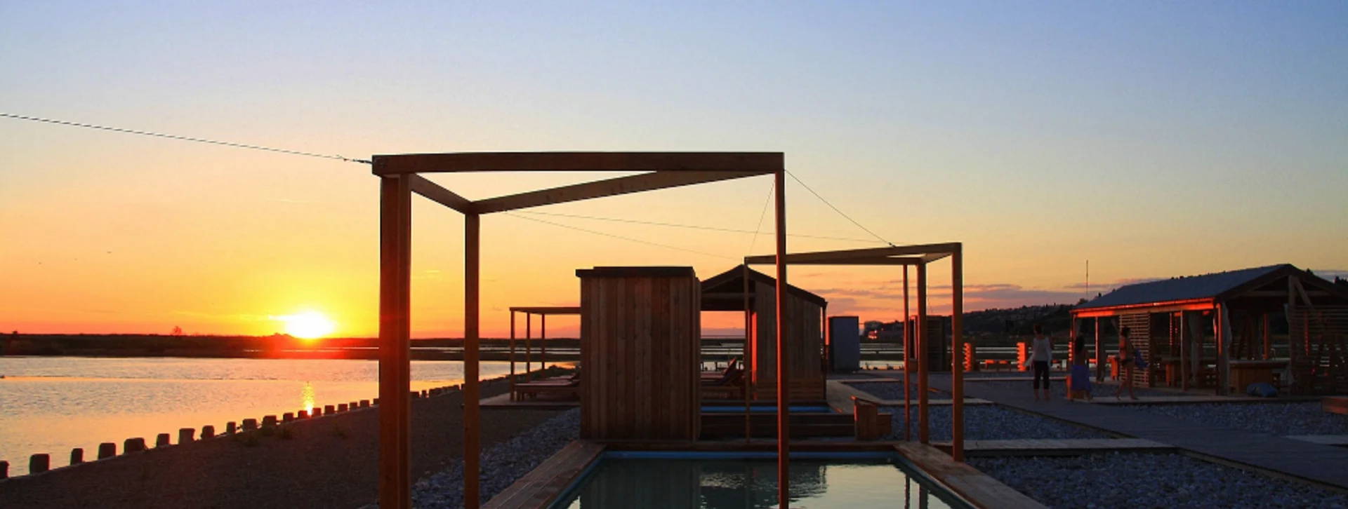 Lepa Vida Open-Air Spa in Slovenia at sunset, with wooden pools overlooking salt pans.