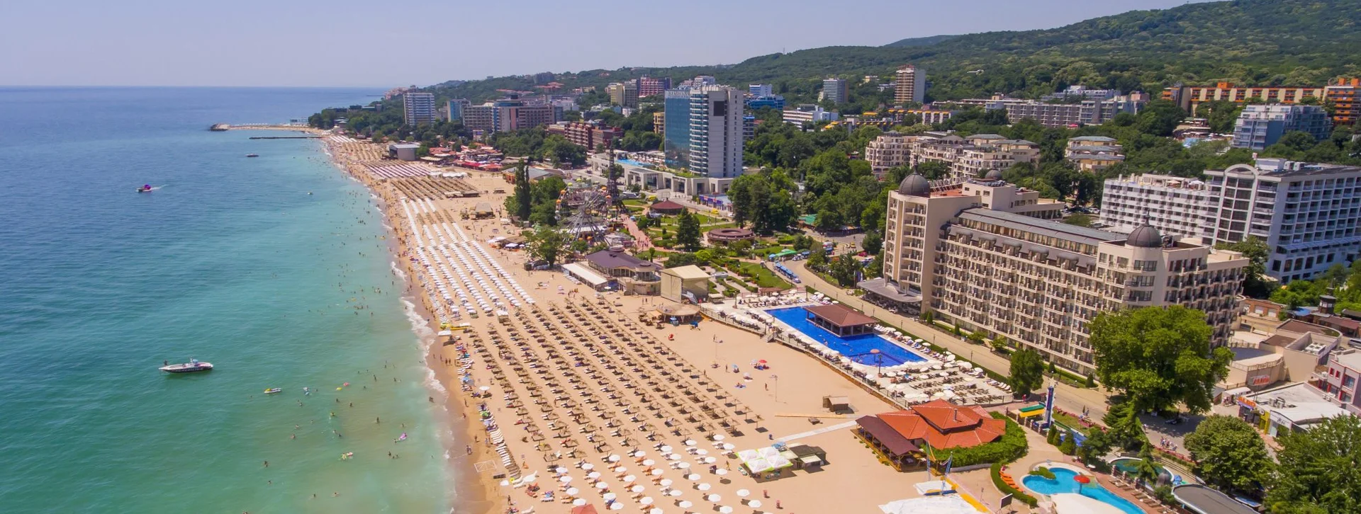 “Golden Sands beach on the Black Sea coast, Bulgaria — wide stretch of golden sand with clear blue water and forested hills behind.